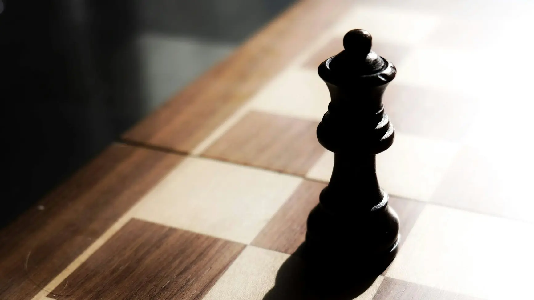 black chess piece on brown and white checkered table