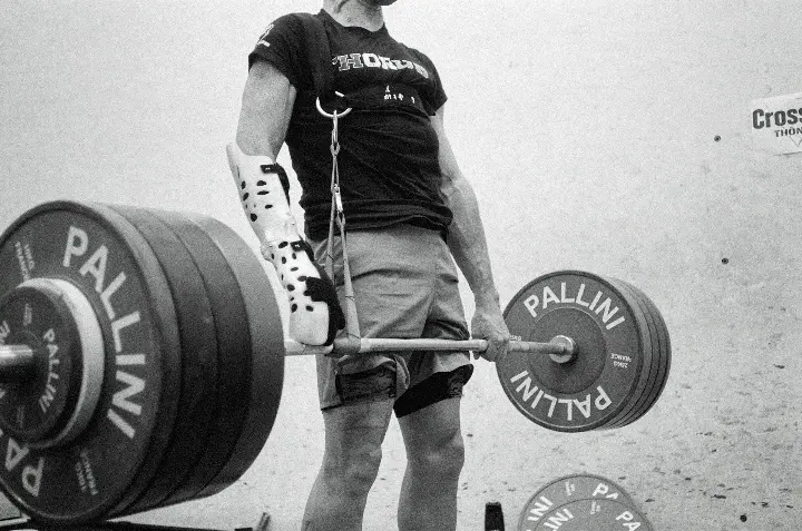 a man holding a barbell in front of a wall